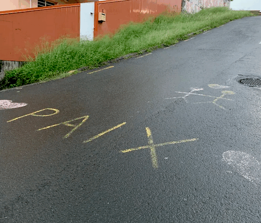 The word "peace" in French is scrawled on the road between Nouméa and Magenta beach