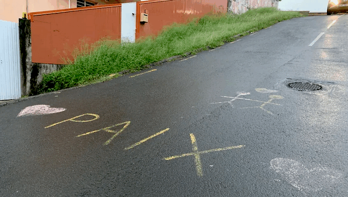 The word "peace" in French is scrawled on the road between Nouméa and Magenta beach