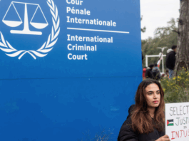 A demonstrator holds a sign reading, "Selective Justice is Injustice"