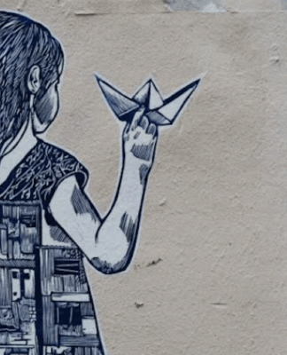 Street art depicting a girl holding a paper boat, with half of her dress showing buildings