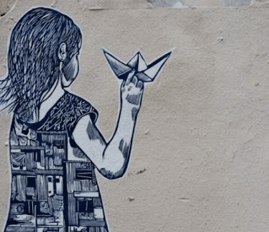 Street art depicting a girl holding a paper boat, with half of her dress showing buildings