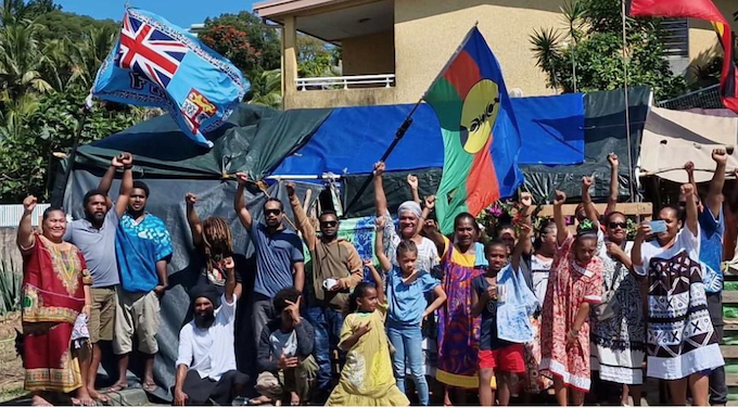 Supporters of Kanak self-determination hold aloft the flags of Fiji and Kanaky