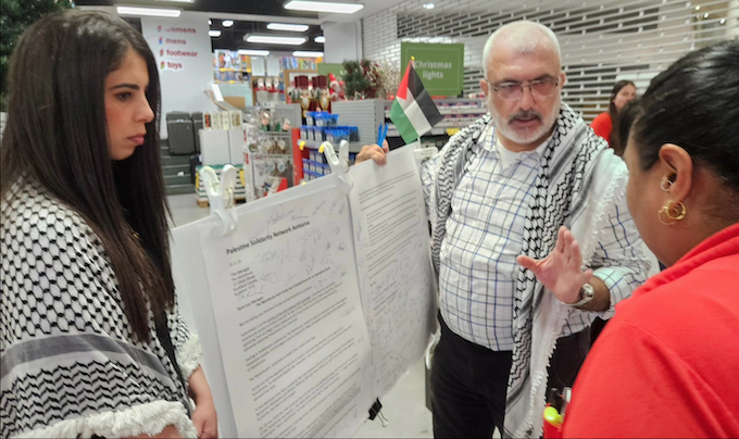 PSNA co-chair Maher Nazzal explains the purpose of the giant protest letter to The Warehouse city branch duty manager Alyce in Auckland today