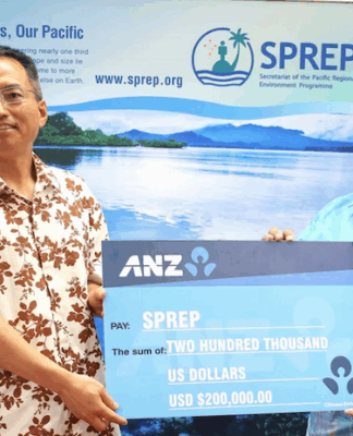 China's ambassador to Samoa Fei Mingxing (left) hands over a ceremonial cheque for US$200,000 to SPREP director of legal services and governing bodies Aumua Clark Peteru in Apia