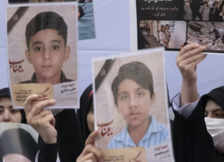 Iranian women hold photos of children who are killed by US-Israeli attacks, including a massacre at a Minab girls’ school that killed around 175 people