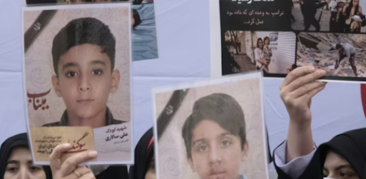 Iranian women hold photos of children who are killed by US-Israeli attacks, including a massacre at a Minab girls’ school that killed around 175 people