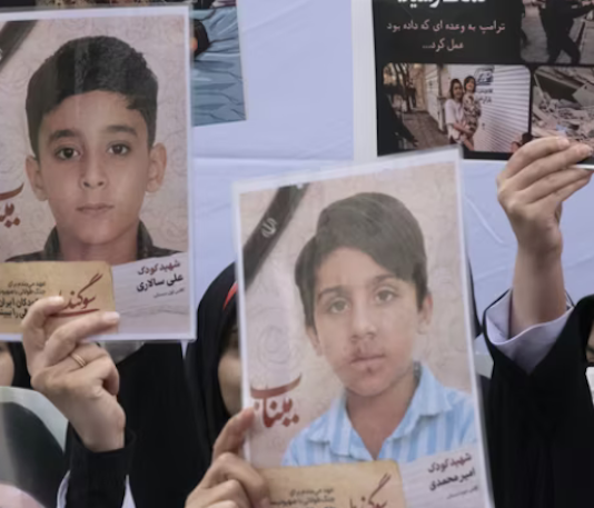 Iranian women hold photos of children who are killed by US-Israeli attacks, including a massacre at a Minab girls’ school that killed around 175 people