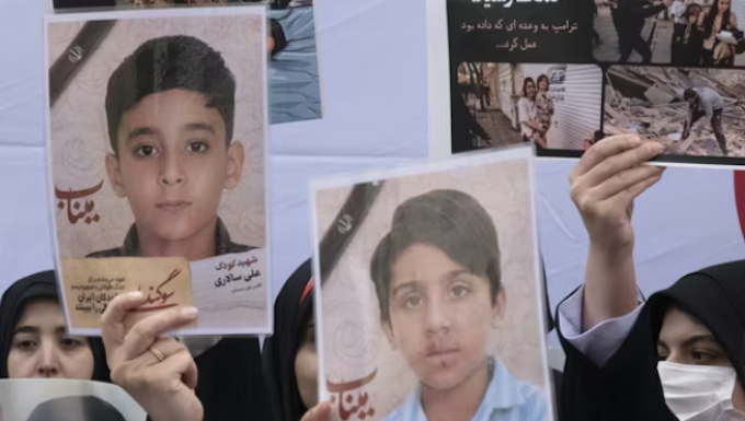 Iranian women hold photos of children who are killed by US-Israeli attacks, including a massacre at a Minab girls’ school that killed around 175 people
