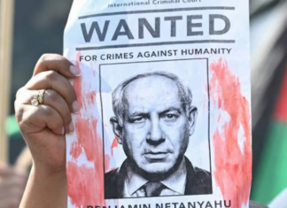 A woman protester holds up a “Wanted” poster featuring Israel’s Prime Minister Benjamin Netanyahu