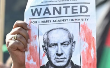 A woman protester holds up a “Wanted” poster featuring Israel’s Prime Minister Benjamin Netanyahu