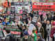 Protesters wave flags and banners reading “Stop Bombing Iran” and “Stop Bombing the Middle East” as they gather at Victoria Tower Gardens in London