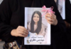 A mourner holds up a picture of one of the victims of the US-Israeli attack on Iran at Minab