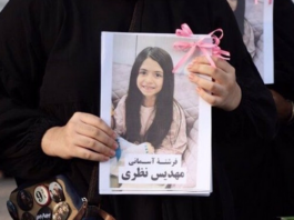 A mourner holds up a picture of one of the victims of the US-Israeli attack on Iran at Minab