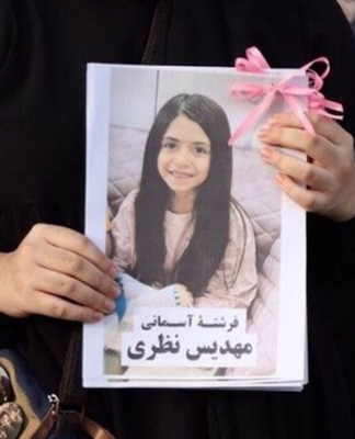 A mourner holds up a picture of one of the victims of the US-Israeli attack on Iran at Minab