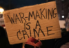 ‘Maniacal tyrant’ Trump and Iran trade threats to energy infrastructure over Strait of Hormuz A US protester holds placards reading ‘’war making is a crime’’