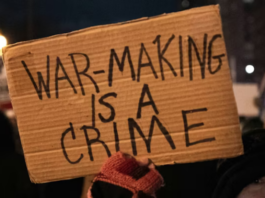 A US protester holds placards reading ‘’war making is a crime’’