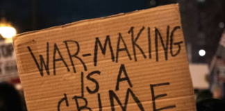 A US protester holds placards reading ‘’war making is a crime’’
