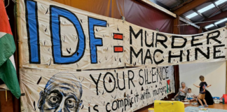 An "IDF = Murder Machine" banner at the "Banners for Humanity" exhibition