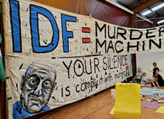 An "IDF = Murder Machine" banner at the "Banners for Humanity" exhibition