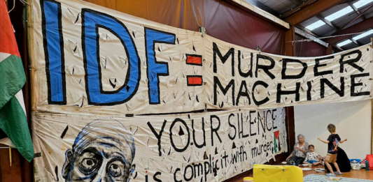An "IDF = Murder Machine" banner at the "Banners for Humanity" exhibition