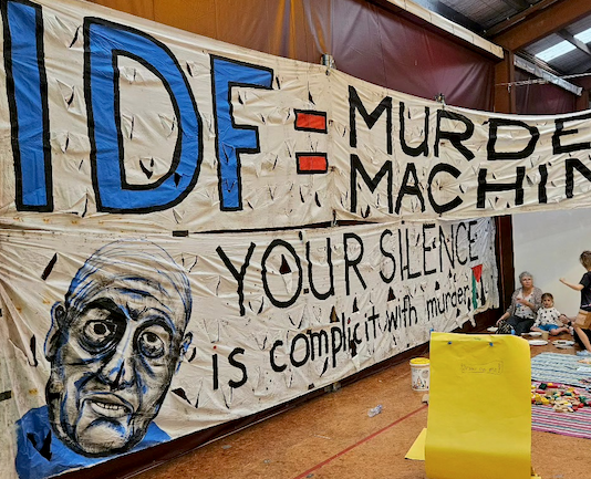 An "IDF = Murder Machine" banner at the "Banners for Humanity" exhibition