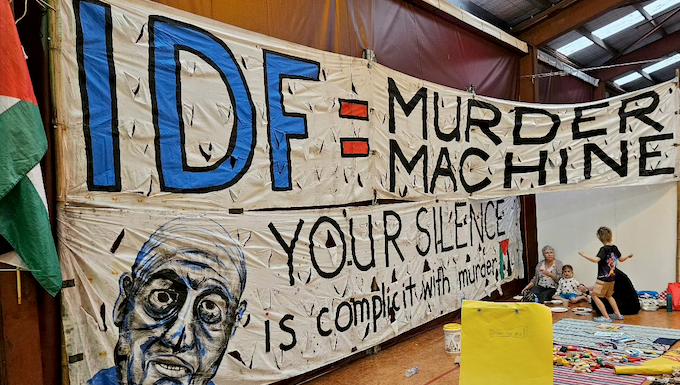 An "IDF = Murder Machine" banner at the "Banners for Humanity" exhibition