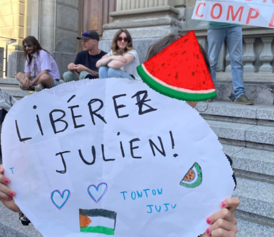 Julien Blondel's niece holds a "free Julien!" placard in French with a Palestinian watermelon logo