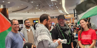 Olivia Coote presents a welcome home koha to Global Sumud Flotilla activists Mousa Taher (centre) and Hāhona Ormsby (black cap) at Auckland International Airport