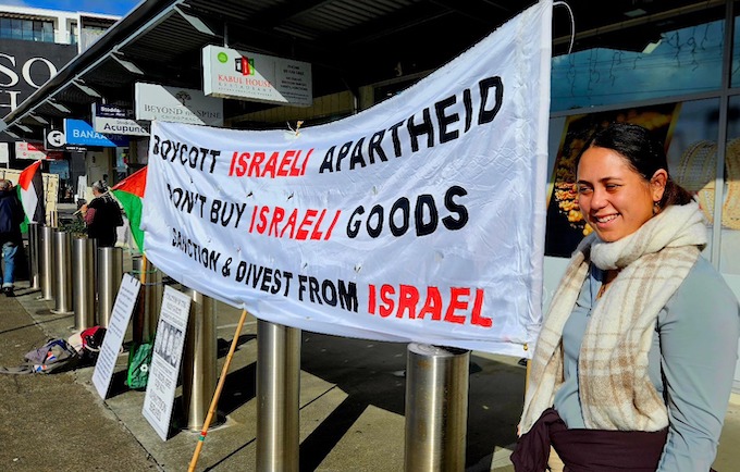 A protester in the picket at the Fiji Consulate in Auckland with a banner calling for sanctions on Fiji