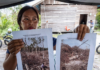 An Indigenous Dayak villager shows pictures of her rubber plantation destroyed