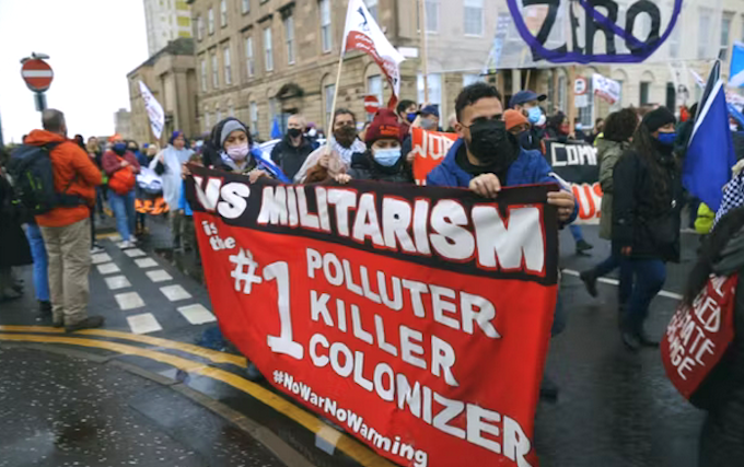 Protesters marching against US militarism at COP26 in Glasgow in a still from Earth’s Greatest Enemy documentary
