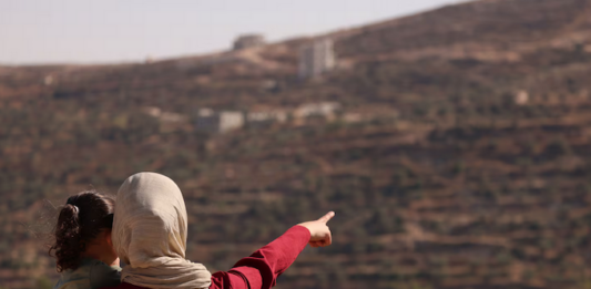 Trapped Palestinian Refqa Hassan watches as Israeli settlers have besieged her family home