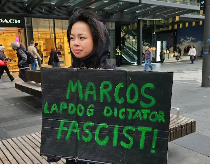 A protester with one of the many "Marcos Lapdog Dictator" placards