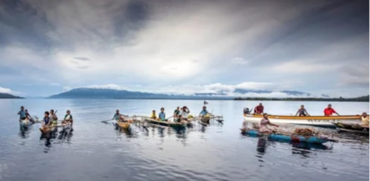 Islanders in outrigger canoes selling tropical fruits off Dobu in the Solomon Sea