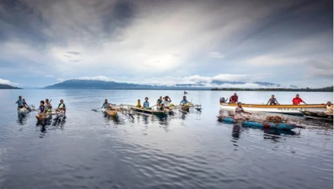 Islanders in outrigger canoes selling tropical fruits off Dobu in the Solomon Sea