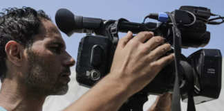 Palestinian journalists work with cameras, laptops and limited equipment from makeshift press areas