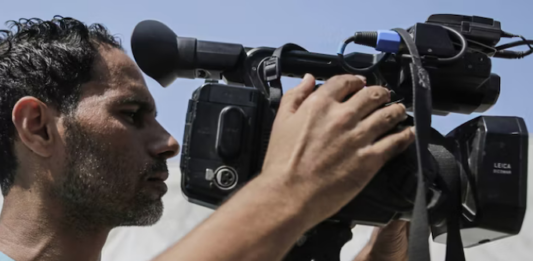 Palestinian journalists work with cameras, laptops and limited equipment from makeshift press areas