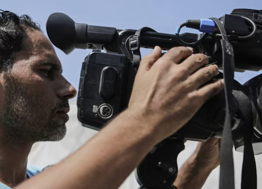Palestinian journalists work with cameras, laptops and limited equipment from makeshift press areas